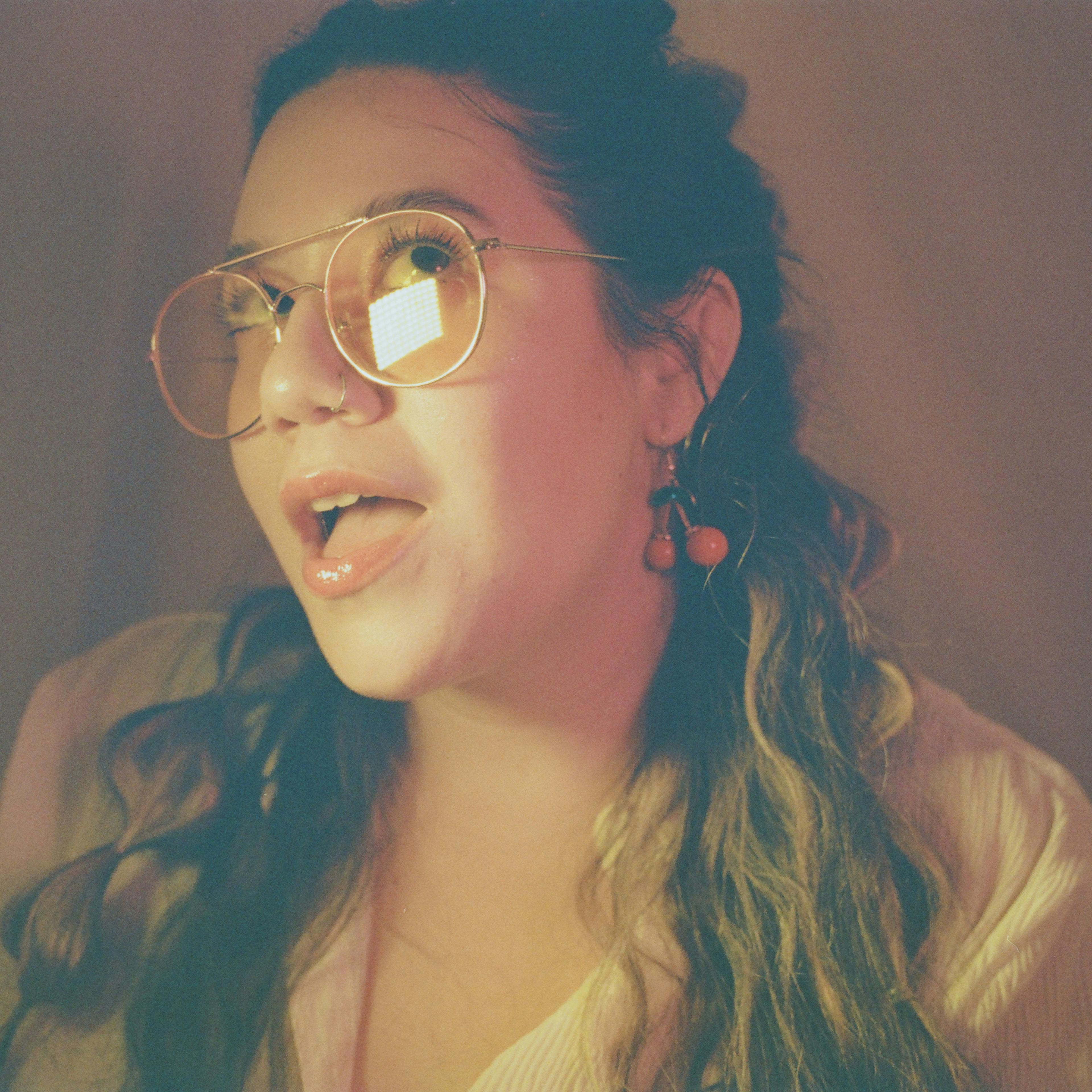 Portrait of woman with studio lighting and cherry earrings on film by Natalie Carrasco