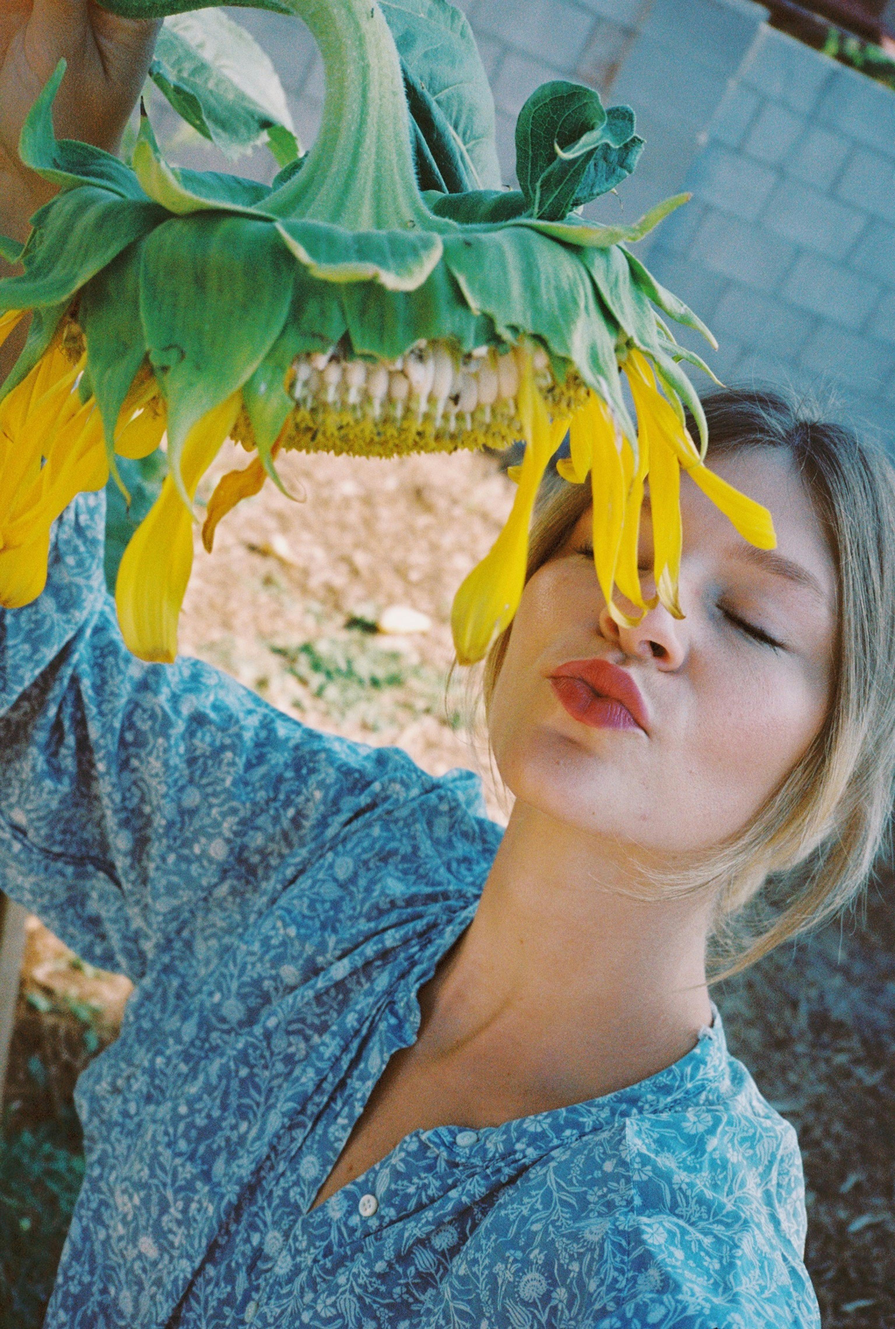 Self portrait of a blonde girl with a giant sunflower on film, by Natalie Carrasco